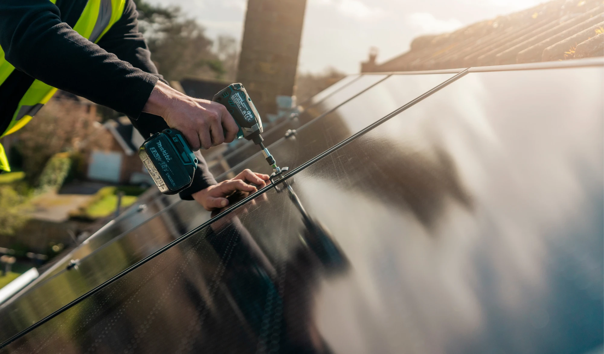 Two Greenscape installers fitting solar panels to a tiled roof