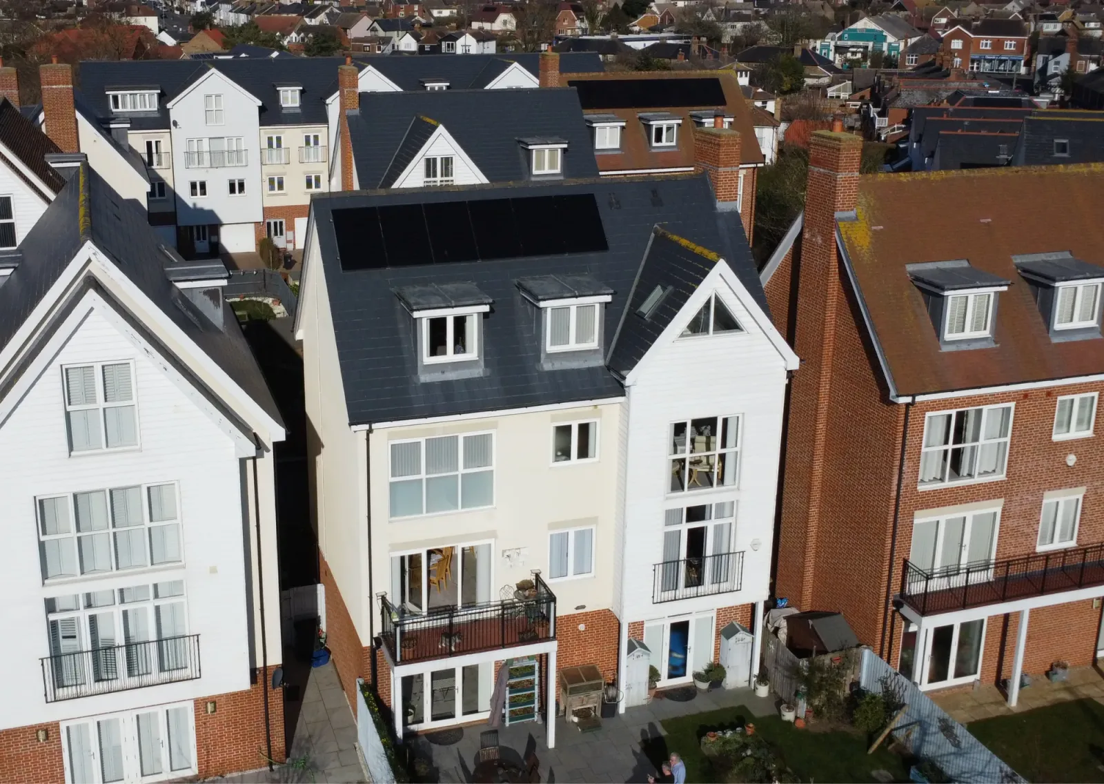 Rear of Delia's tall cream and white home, with black solar panels on the slate roof