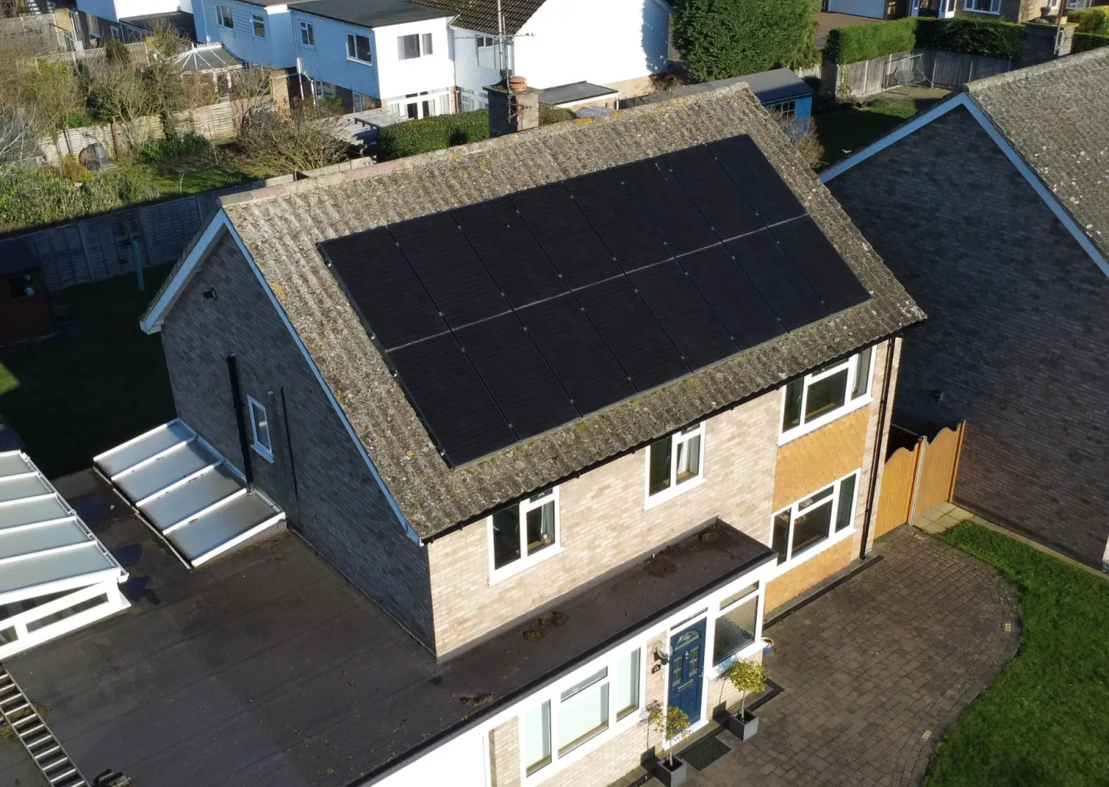 Aerial view of the Brobbins' detached brick house with a large array of black panels on the roof