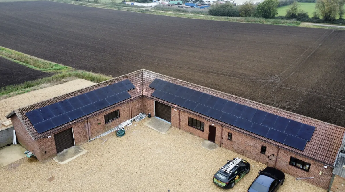 Aerial view of an L-shaped farm building with solar panels