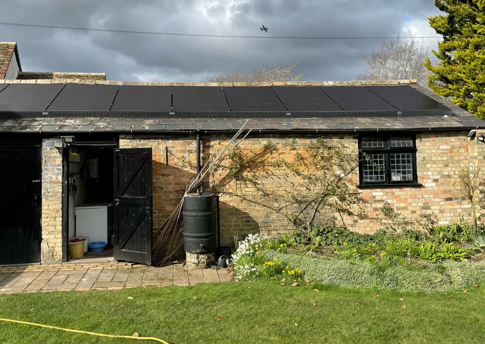 Grace's brick outbuilding with a long array of black solar panels on its slate roof