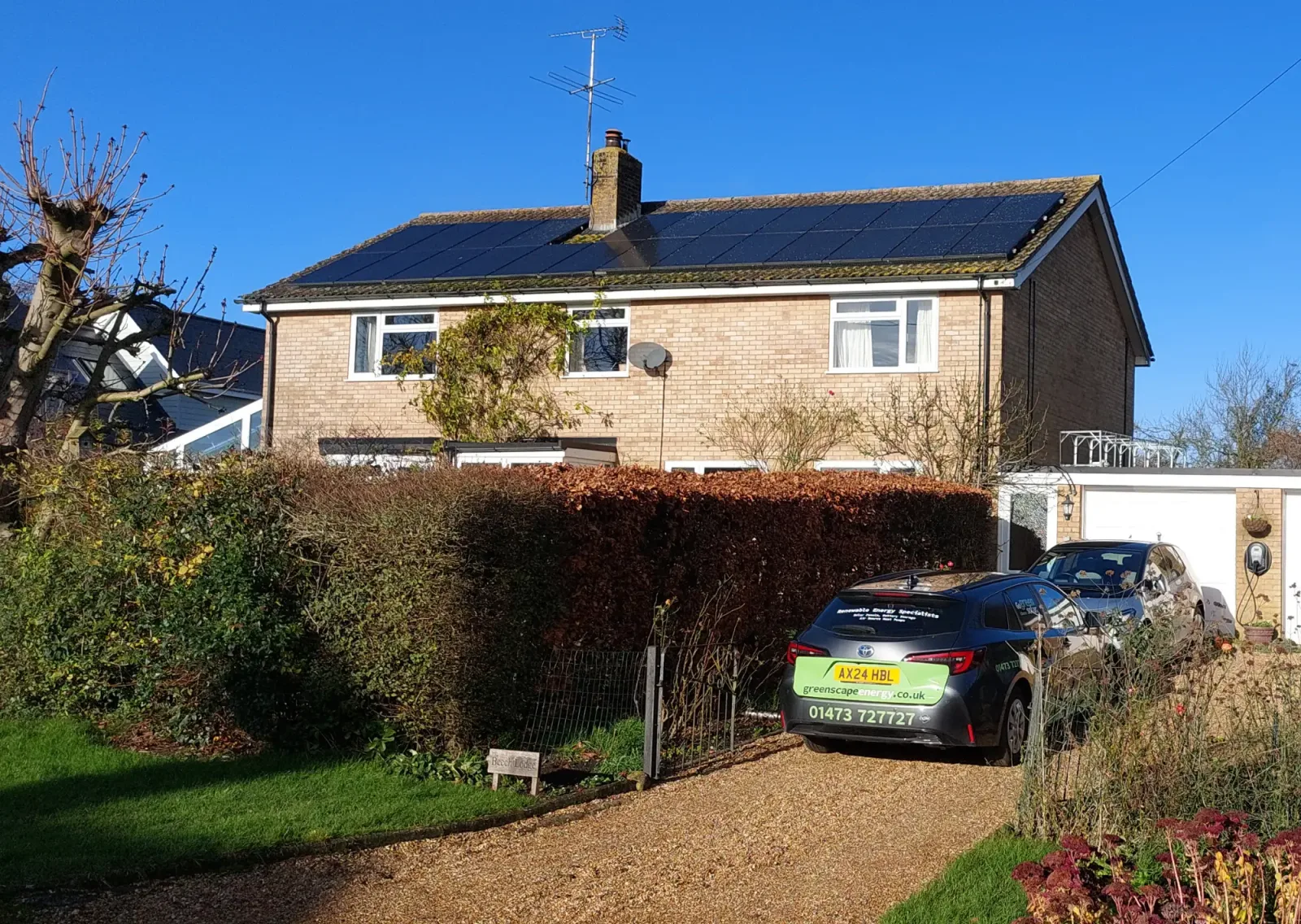Josephine's detached brick home with a long array of black solar panels and a Greenscape car on the drive