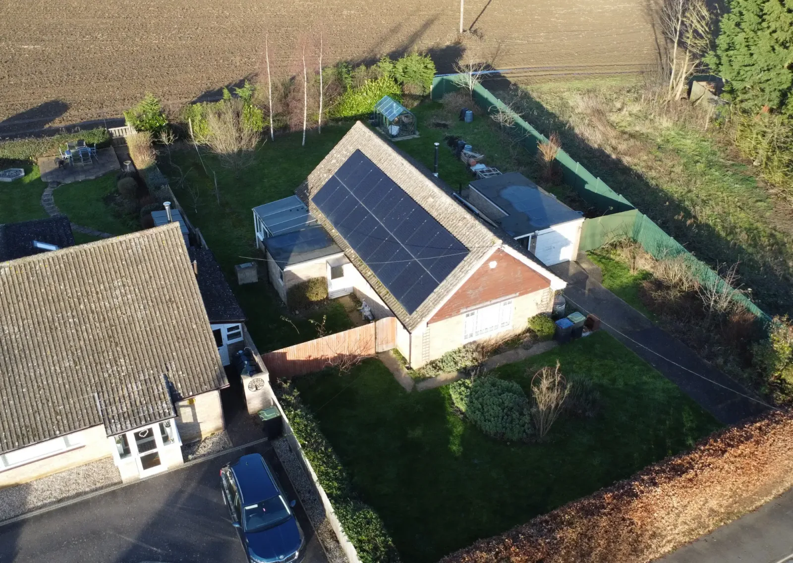 Aerial view of Beth's bungalow with a large array of black solar panels on one roof slope