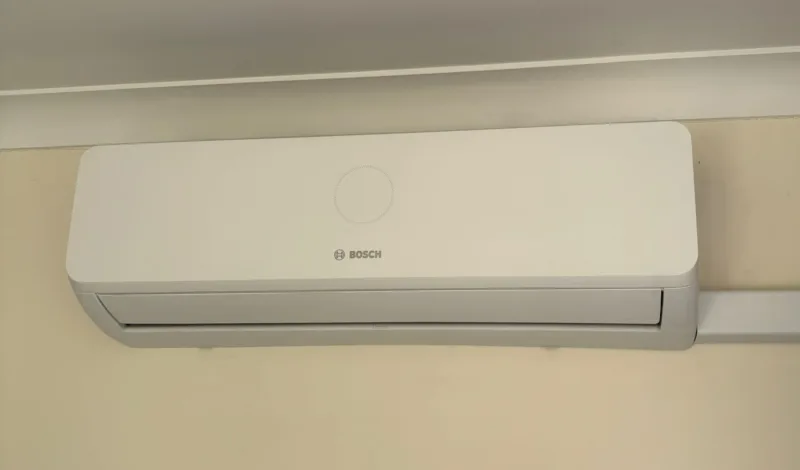 A Bosch indoor wall unit on a cream wall below white coving, with trunking beside it