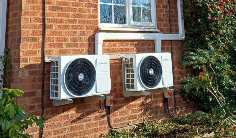 Two Bosch outdoor units side by side on a red-brick wall under a window