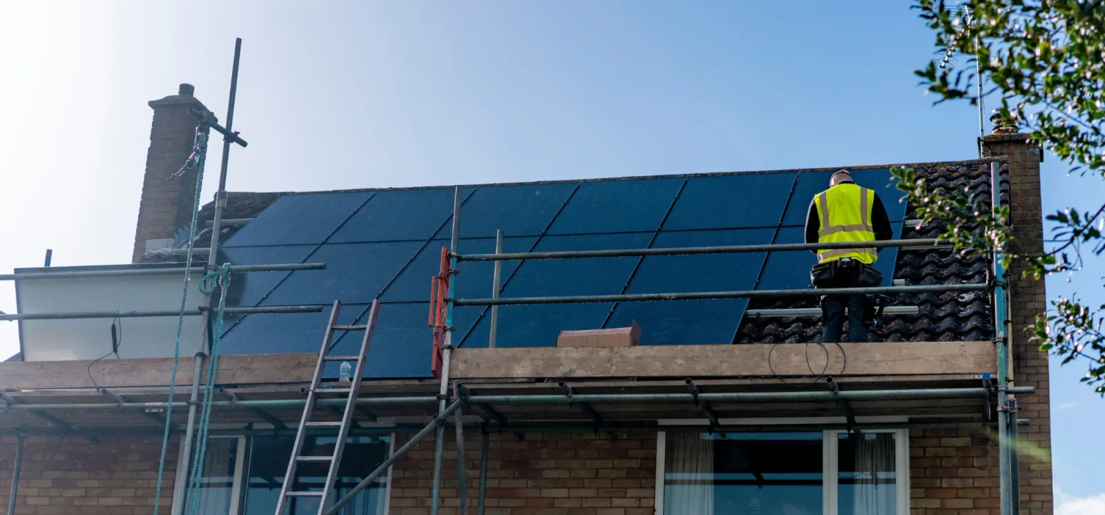 Greenscape installers fitting solar panels on a scaffolded roof