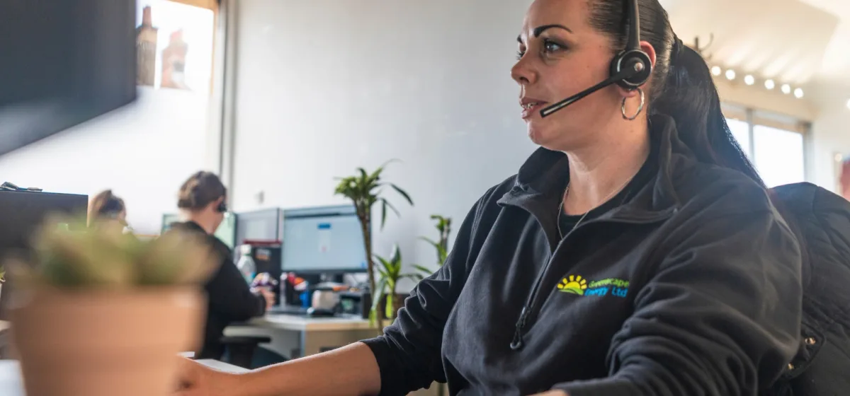 A Greenscape team member in a headset taking a call in the office