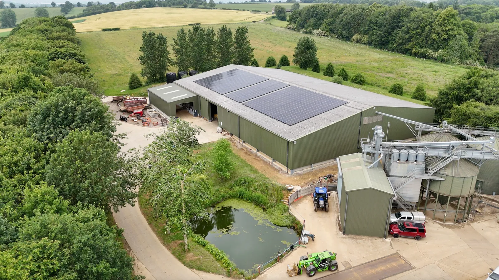 A farmyard seen from above, its main building roofed with solar panels
