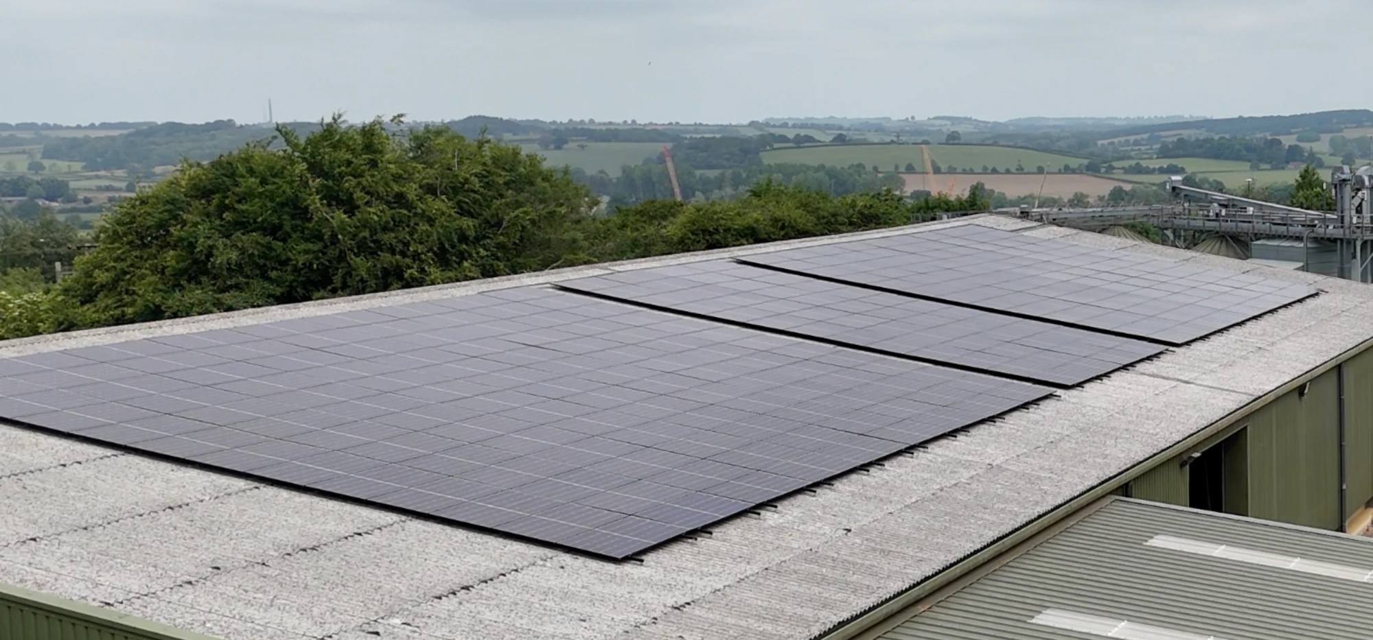 A farm shed with a solar roof, ringed by trees