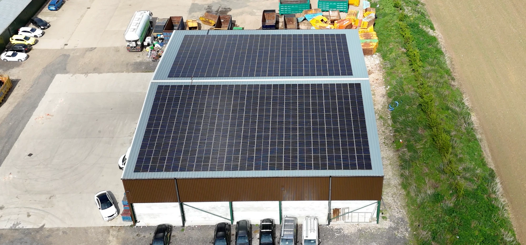 Three installers lifting a panel onto a farm building roof