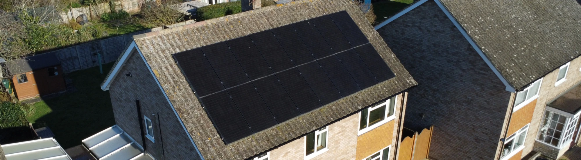 Two Greenscape installers working along a run of roof-mounted panels
