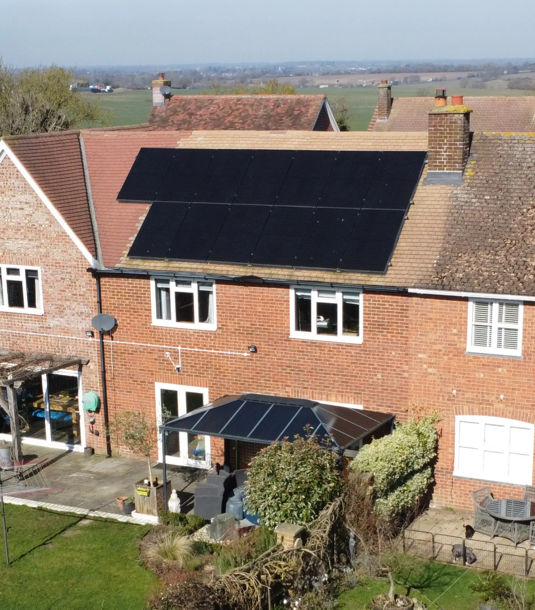 Two Greenscape installers fitting a run of solar panels to a tiled roof