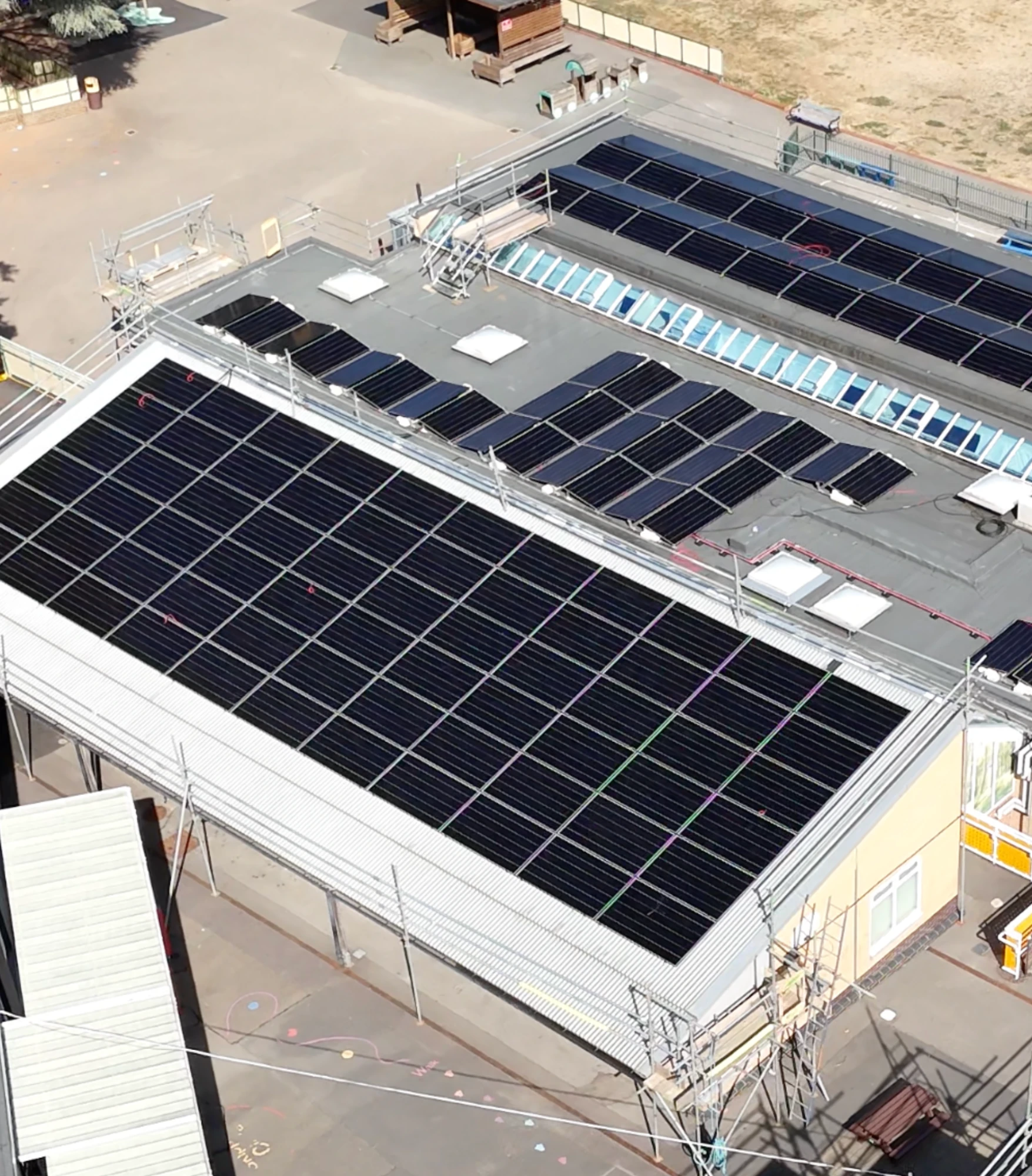 An office building with solar panels on its roof, beside a car park