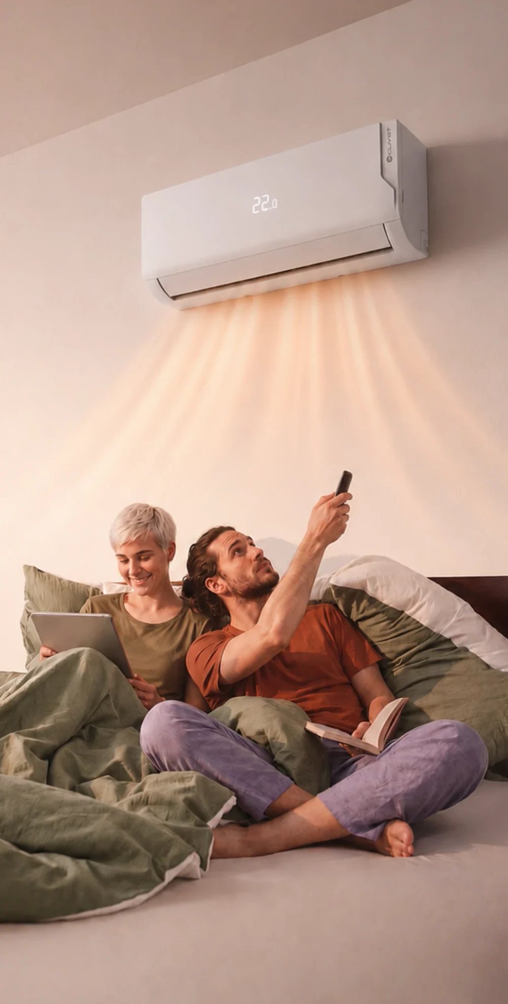 A couple in bed under a Clivet wall unit, adjusting the temperature with a remote