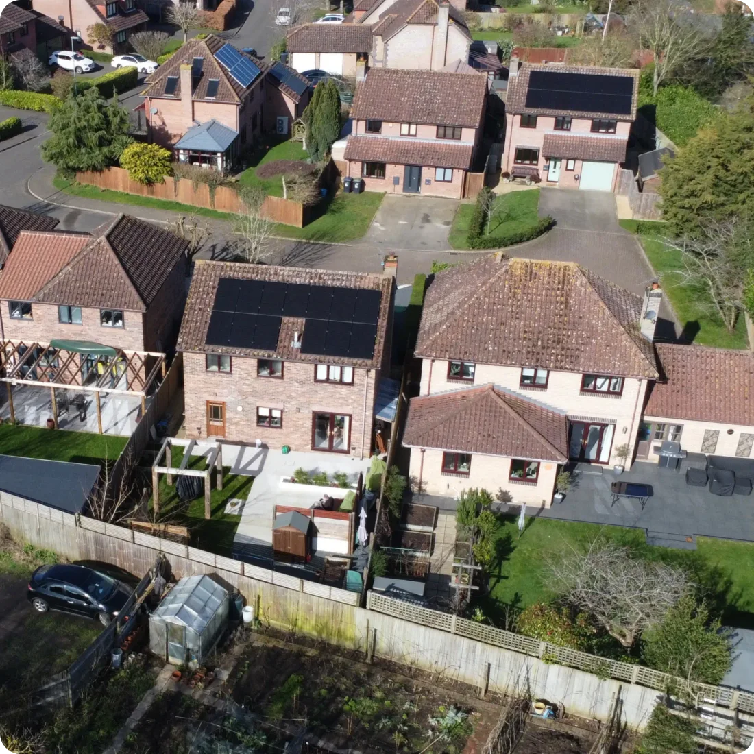 An aerial view of a row of brick houses, one with solar panels on its tiled roof